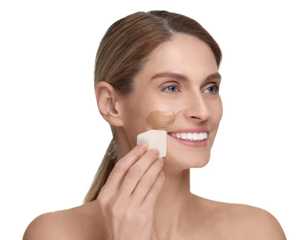 白い背景に化粧スポンジで顔に財団を適用する女性 — ストック写真