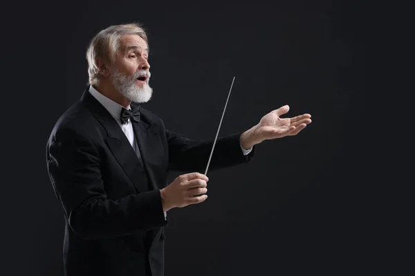 stock image Professional conductor with baton on black background