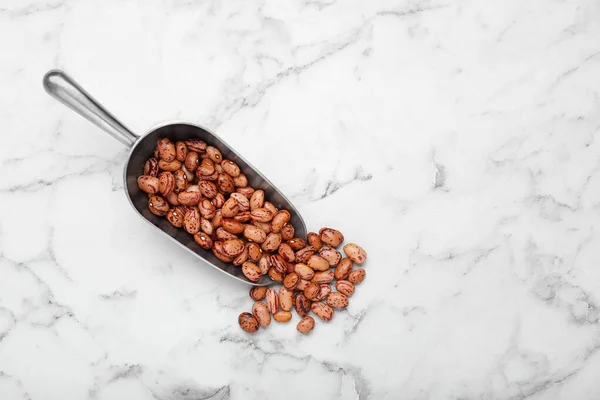 stock image Metal scoop with dry kidney beans on white marble table, flat lay. Space for text