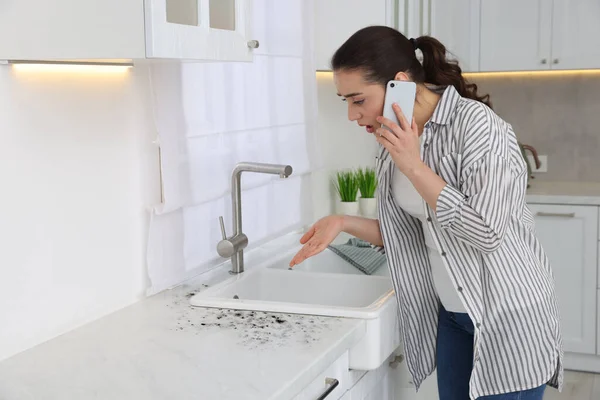 Küf Temizleme Servisi Kadın Telefonda Konuşuyor Mutfaktaki Etkilenmiş Bölgeye Bakıyor — Stok fotoğraf