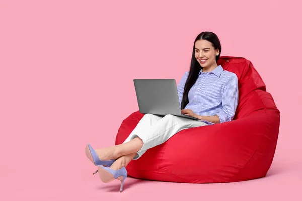 Glückliche Frau Mit Laptop Sitzt Auf Sitzsack Stuhl Vor Rosa — Stockfoto