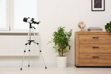Moda odasında modern teleskopu olan tripod.