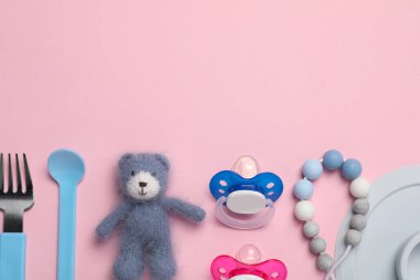 Düz kompozisyon, emzikler ve pembe arka planda diğer bebek eşyaları. Metin için boşluk