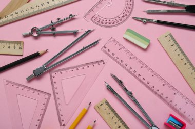 Pembe zemin üzerinde farklı cetvel ve kırtasiye ile düz kompozisyon