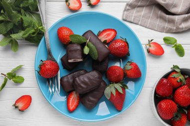 Lezzetli kremalı aperatifler, nane yaprakları ve beyaz ahşap masada taze çilekler.