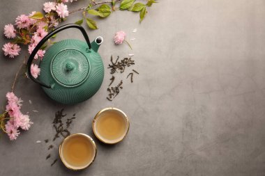 Geleneksel tören. Çay fincanları, çaydanlık ve sakura çiçekleri gri masada, düzlük ve metin için yer var.