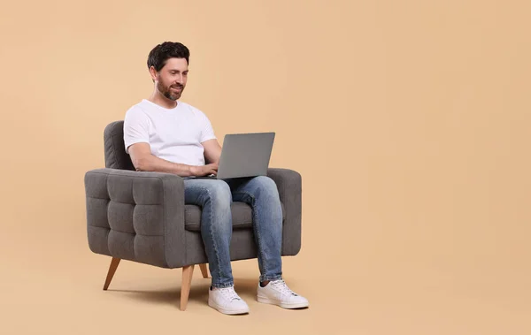 Homem Feliz Com Laptop Sentado Poltrona Contra Fundo Bege Espaço — Fotografia de Stock