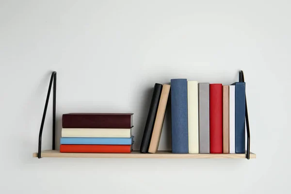 白色墙壁上有许多精装书的木制书架 — 图库照片