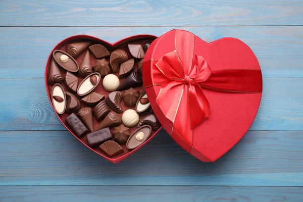 心形盒子 浅蓝色木制桌子上有美味的巧克力糖果 顶部观景 — 图库照片