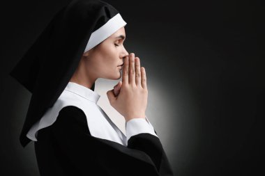 Elleri sımsıkı bağlı rahibe siyah arka planda Tanrı 'ya dua ediyor. Metin için boşluk