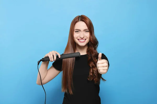 Schöne Frau Mit Haarbügeleisen Zeigt Daumen Nach Oben Auf Hellblauem — Stockfoto
