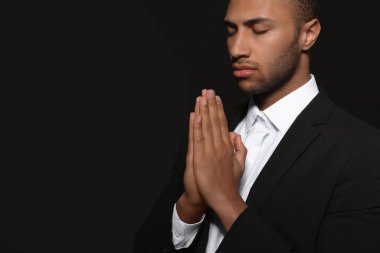 Siyah arka planda Tanrı 'ya dua eden elleri sımsıkı bağlı Afrikalı Amerikalı bir adam. Metin için boşluk