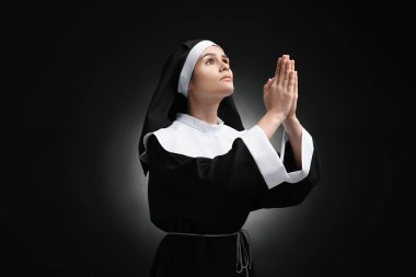 Elleri sımsıkı bağlı rahibe siyah arka planda Tanrı 'ya dua ediyor.