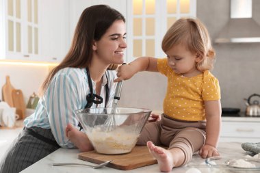 Anne ve küçük kızı mutfakta birlikte hamur pişiriyorlar.