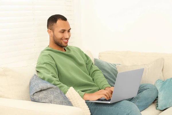 アフリカ系アメリカ人男性タイプのラップトップ上のソファで部屋 — ストック写真