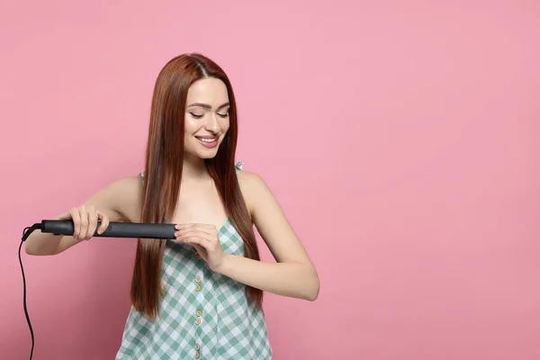 Όμορφη Γυναίκα Χρησιμοποιώντας Σίδερο Μαλλιών Ροζ Φόντο Χώρος Για Κείμενο — Φωτογραφία Αρχείου