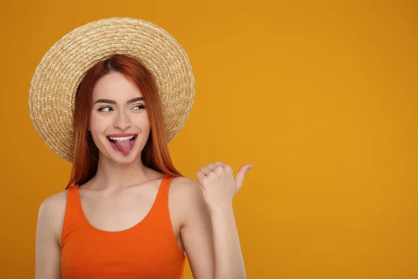 Szczęśliwa Kobieta Pokazuje Swój Język Wskazuje Coś Pomarańczowym Tle Miejsce — Zdjęcie stockowe