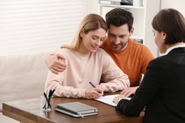 Professional notary helping couple with paperwork in office