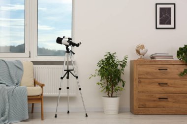 Moda odasında modern teleskopu olan tripod.