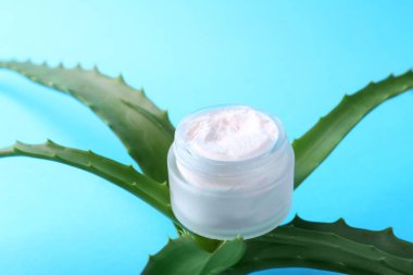 Açık mavi arkaplanda Aloe yaprakları ve kozmetik ürünü