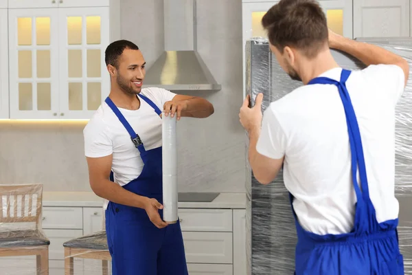 Yeni Evde Streç Film Ambalajlı Buzdolabı Taşıyan Erkek Nakliyeciler — Stok fotoğraf