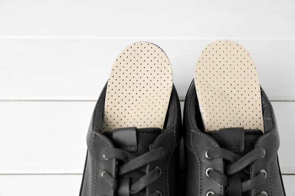 在白色木制地板上穿着鞋的矫形外科鞋底 案文的篇幅 — 图库照片