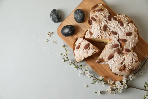 Lezzetli İtalyan Paskalya güvercini pastası (geleneksel Colomba di Pasqua), açık gri masa üzerinde boyanmış yumurta ve çiçekli dallar, düzlük. Metin için boşluk