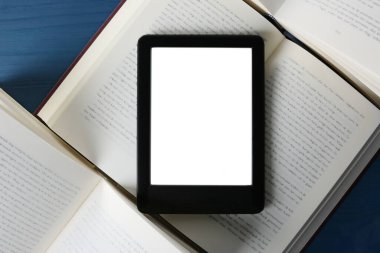 Taşınabilir e-kitap okuyucu ve mavi ahşap masa üzerinde ciltli kitaplar, düz uzanma