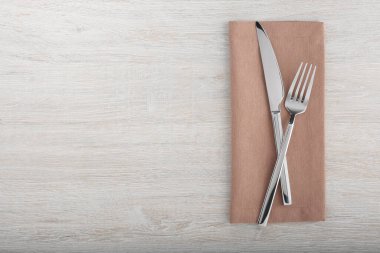 Parlak çatal, bıçak ve peçete beyaz ahşap masada, düz yerde. Metin için boşluk