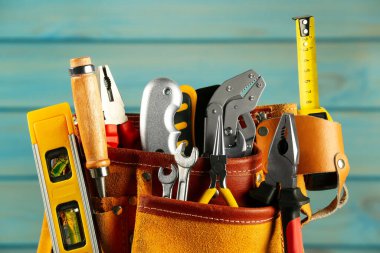 Açık mavi ahşap arka planda farklı araçlara sahip kemer, yakın plan