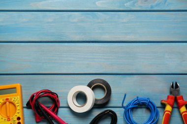 Kablolar ve elektrikli aletler açık mavi ahşap masada, düz yerde. Metin için boşluk