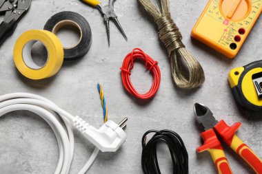 Gri masa üzerinde yeni kablolar ve elektrikçi aletleri düz yatıyordu