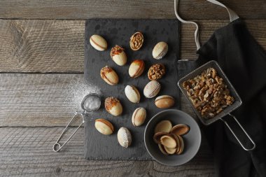 Taze pişirilmiş ev yapımı ceviz şekilli kurabiyeler, fındık ve un ahşap masada, düz yatıyordu. Metin için boşluk