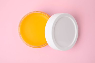 Pembe arka planda petrolatum olan kavanozu aç, üst görünümde