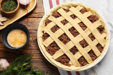 Çiğ et turtası ve malzemeler ahşap masada, düz yerde.