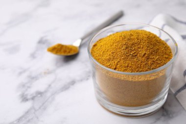 Beyaz mermer masanın üzerinde köri tozu olan cam, yakın plan. Metin için boşluk