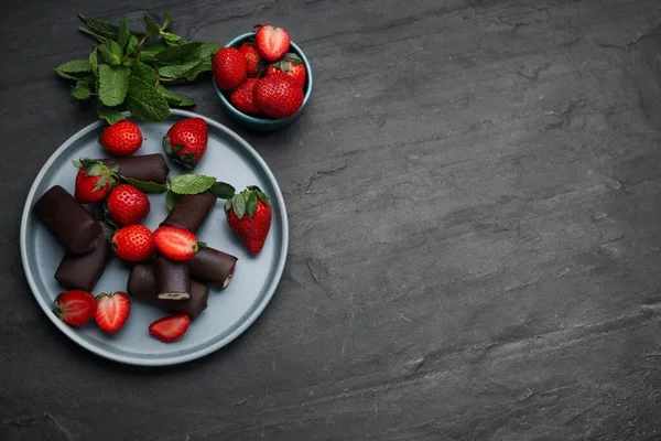 Delicious glazed curd snacks with fresh strawberries and mint on black table, flat lay. Space for text