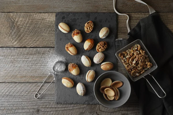 Taze pişirilmiş ev yapımı ceviz şekilli kurabiyeler, fındık ve un ahşap masada, düz yatıyordu. Metin için boşluk