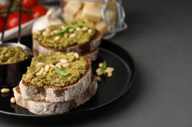Pesto soslu lezzetli bruschettalar ve koyu gri masada fındıklar, yakın plan. Metin için boşluk