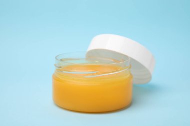 Açık mavi arkaplanda petrolatum kavanozunu aç, kapat