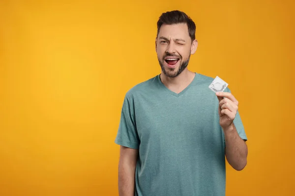 Excited Man Holding Condom Orange Background Space Text — Stock Photo, Image