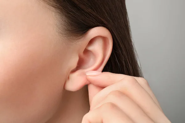 Woman Touching Her Ear Light Grey Background Closeup — Stock Photo, Image
