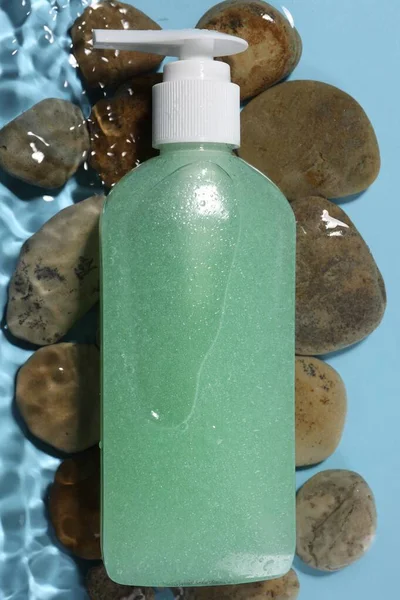 Μπουκάλι Καθαριστικό Προσώπου Και Πέτρες Στο Νερό Ανοιχτό Μπλε Φόντο — Φωτογραφία Αρχείου