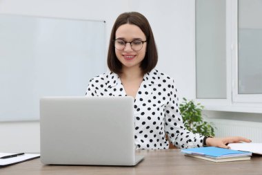 Modern ofiste dizüstü bilgisayarla çalışan genç ve mutlu bir stajyer.