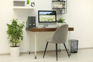 Samimi çalışma alanı, ahşap masa üzerinde bilgisayar ve evdeki rahat sandalye.