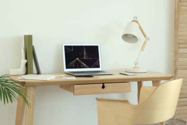 Cozy workspace with modern laptop on desk and comfortable chair at home