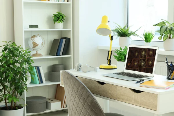 Cozy workspace with laptop on white wooden desk at home