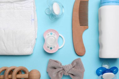 Flat lay composition with pacifiers and other baby stuff on light blue background