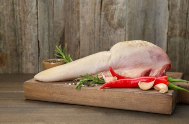 Çiğ sığır dili, biber, sarımsak, tuz, biberiye ve ahşap masada kırmızı biber.