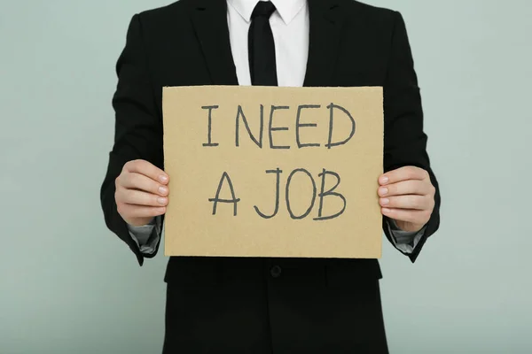失業中の男がサインを持っている私はライトグレーの背景に仕事が必要 クローズアップ — ストック写真